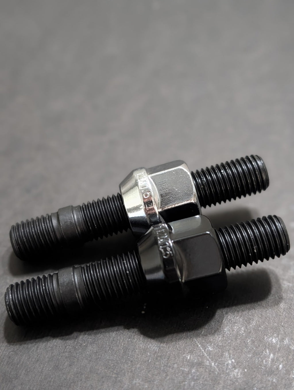 Close-up of two black wheel studs with chrome wheel nuts