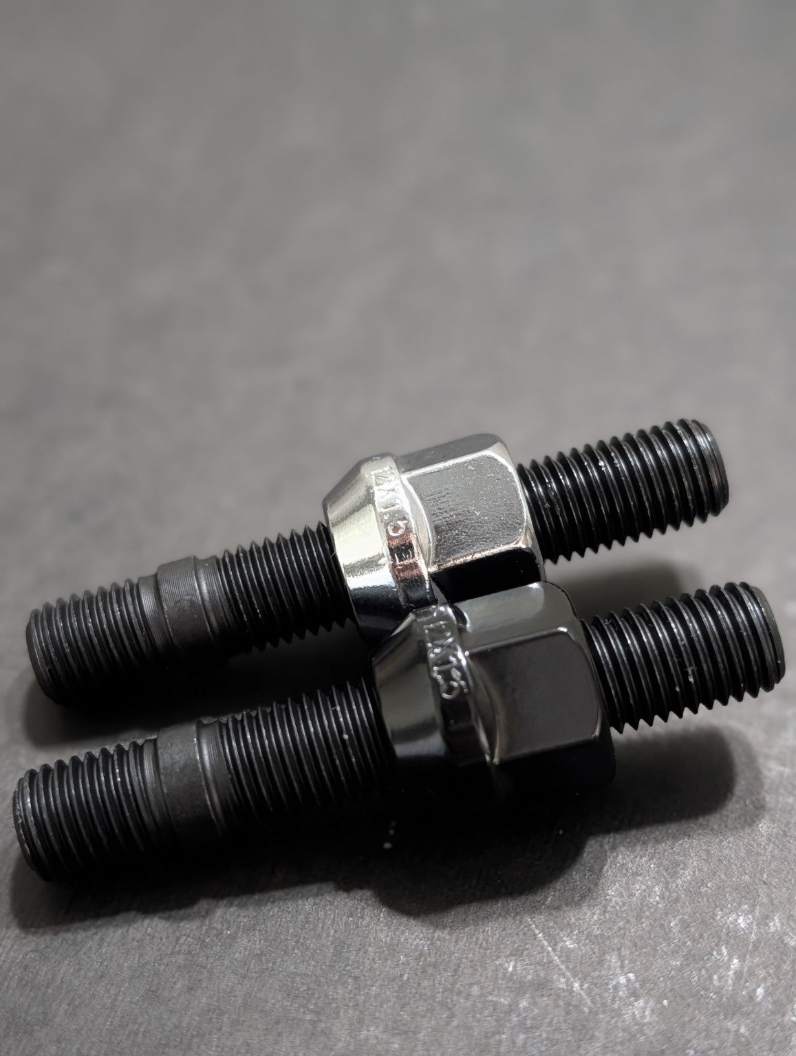 Close-up of two black wheel studs with chrome wheel nuts