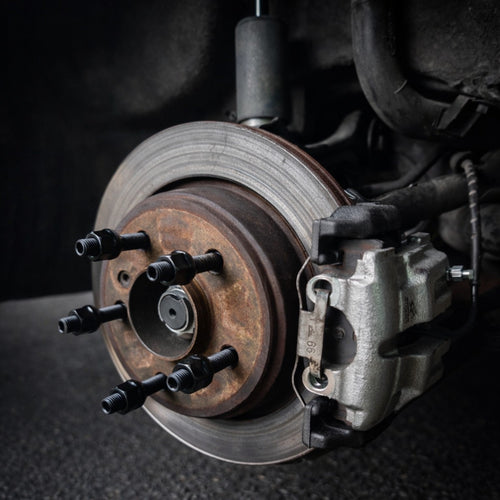 E9X AutoHaus brake kit installed with a new caliper, painted carrier and wheel studs with black nuts
