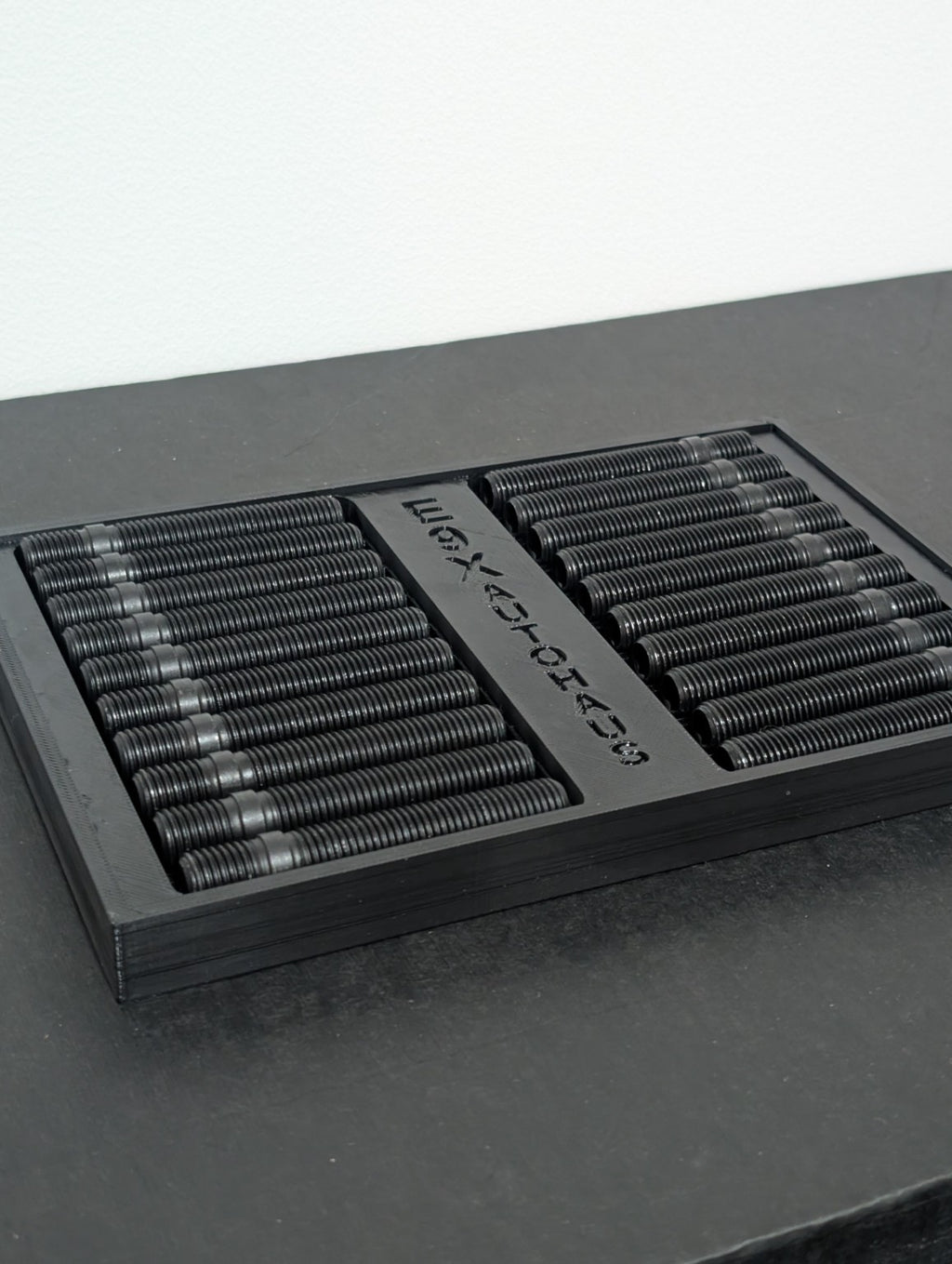 E9X AutoHaus wheel studs arranged in a branded display tray